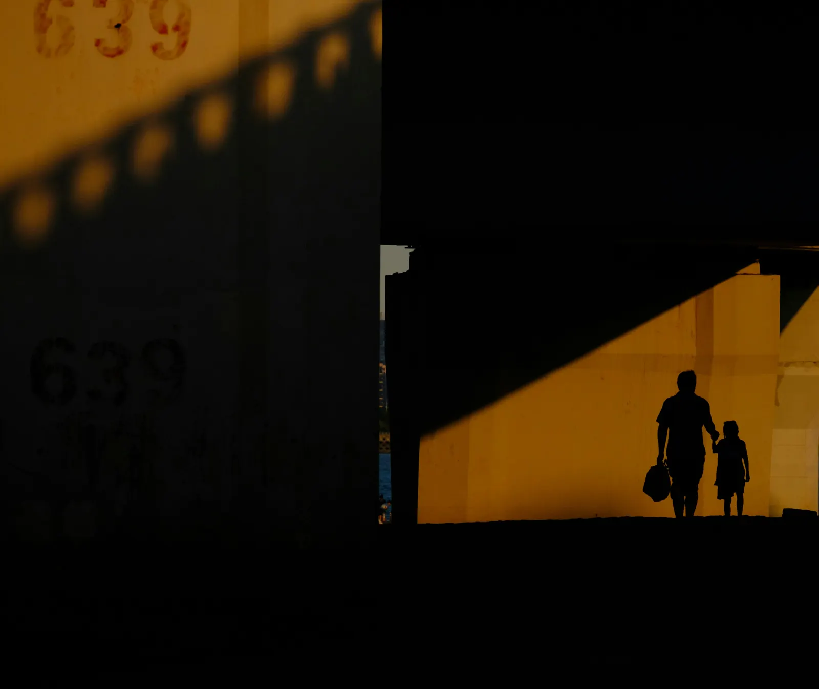 Silhouette of a father and child walking hand in hand at dusk